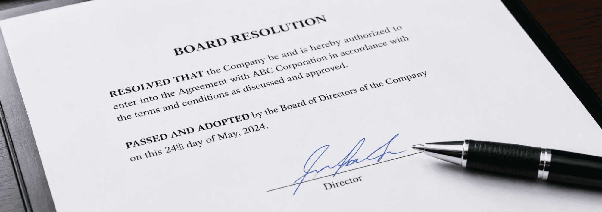 Close-up of a signed board resolution document with a pen resting on the signature line.
